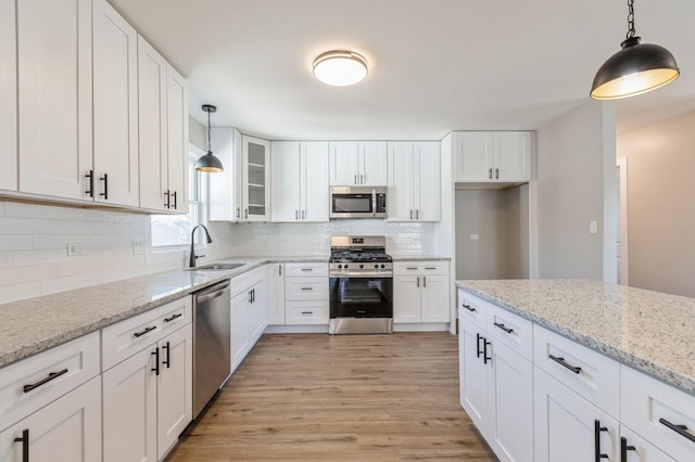 kitchen featuring sink, white cabinets, decorative light fixtures, and stainless steel appliances