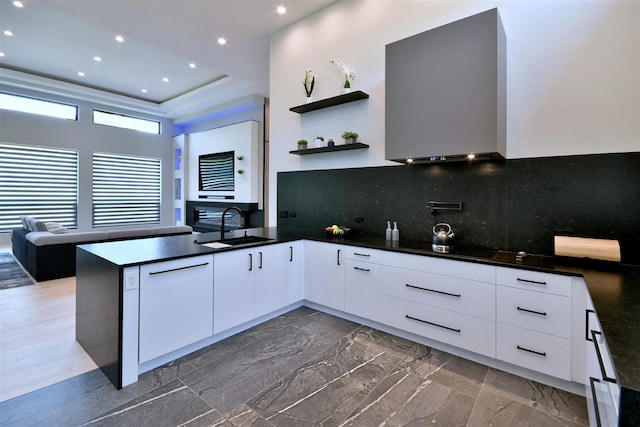 kitchen featuring kitchen peninsula, sink, tasteful backsplash, and white cabinetry