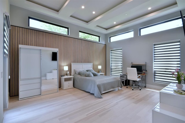 bedroom featuring coffered ceiling, light hardwood / wood-style floors, and a towering ceiling