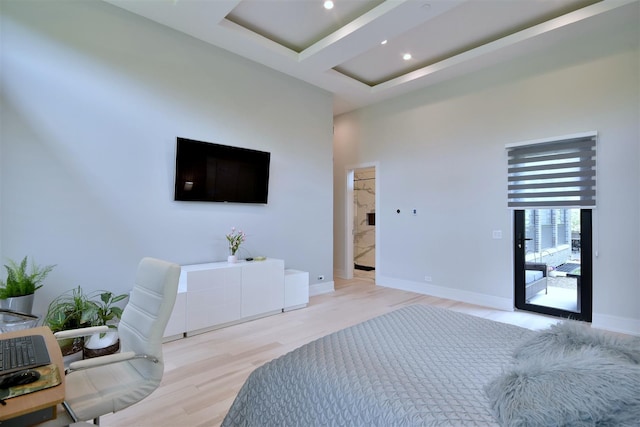 bedroom featuring light hardwood / wood-style flooring, a towering ceiling, ensuite bath, and access to outside