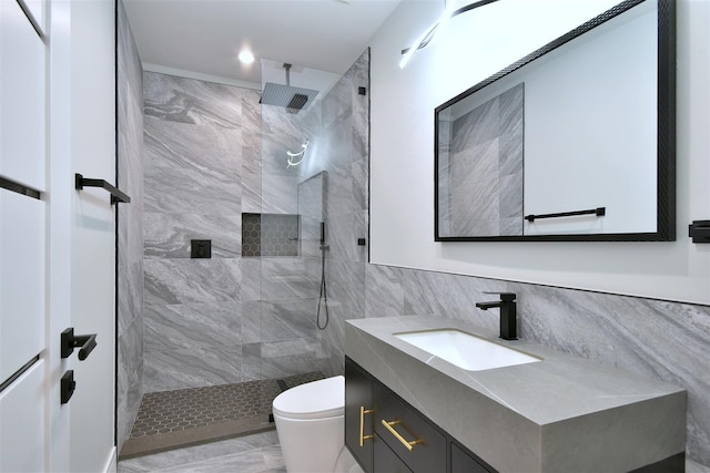 bathroom with vanity, toilet, tile walls, and a tile shower