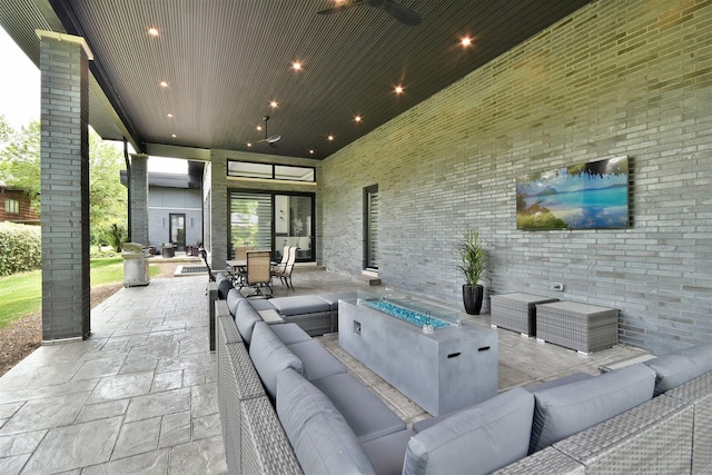 view of patio / terrace with ceiling fan and an outdoor living space with a fire pit