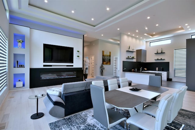 dining room with a towering ceiling, light hardwood / wood-style floors, and a tray ceiling