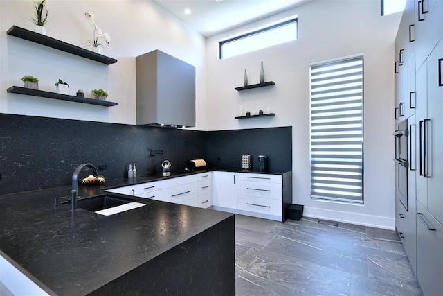 kitchen with sink, backsplash, white cabinetry, and a high ceiling