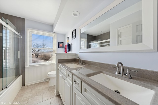 full bathroom featuring bath / shower combo with glass door, vanity, tile patterned floors, and toilet