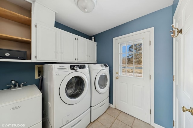 clothes washing area featuring separate washer and dryer, light tile patterned floors, sink, and cabinets