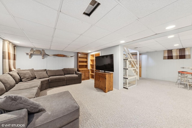 carpeted living room featuring a drop ceiling