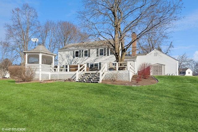 rear view of property with a wooden deck, a gazebo, and a lawn