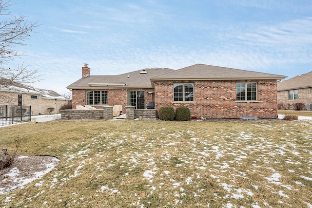 snow covered rear of property featuring a yard