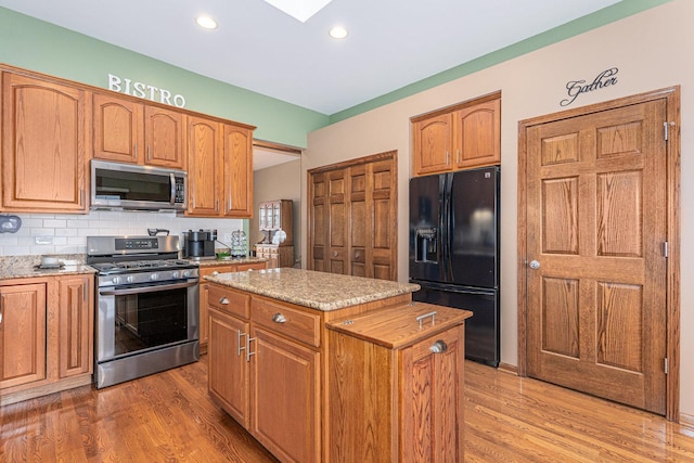 kitchen with a kitchen island, hardwood / wood-style floors, backsplash, and stainless steel appliances