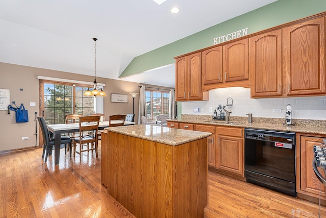 kitchen featuring a kitchen island, hanging light fixtures, black dishwasher, and light stone countertops