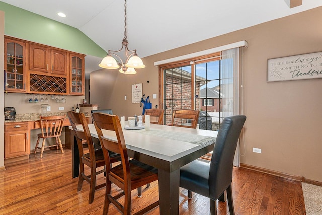 dining space with dark wood-type flooring, a chandelier, and vaulted ceiling