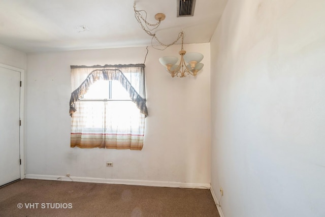 spare room with a notable chandelier and carpet