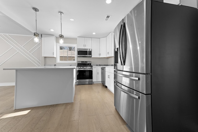 kitchen featuring light hardwood / wood-style flooring, stainless steel appliances, white cabinets, and a kitchen island