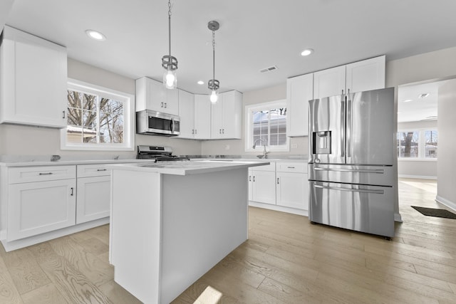 kitchen featuring white cabinetry, decorative light fixtures, and appliances with stainless steel finishes