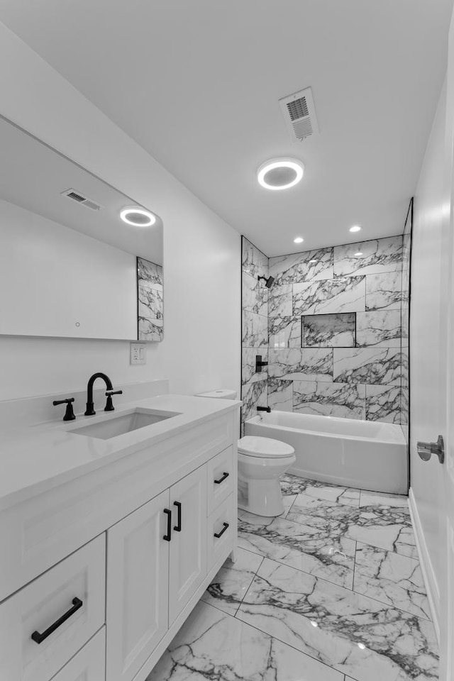 full bathroom with tiled shower / bath, vanity, and toilet