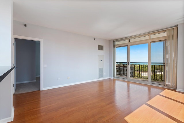 empty room with hardwood / wood-style floors and expansive windows