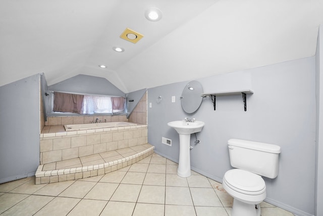 bathroom with tiled tub, vaulted ceiling, tile patterned flooring, and toilet