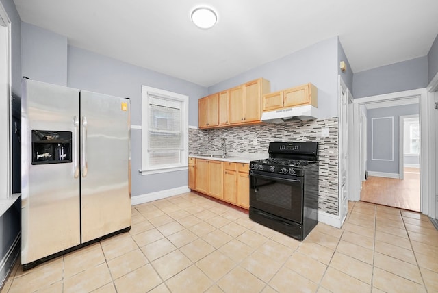 kitchen with light tile patterned floors, black range with gas cooktop, light brown cabinetry, stainless steel fridge with ice dispenser, and decorative backsplash