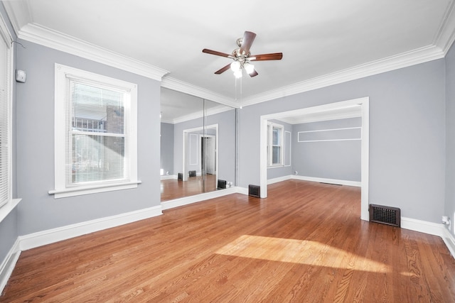 unfurnished living room featuring wood-type flooring, ornamental molding, and ceiling fan