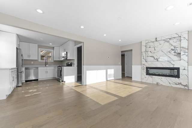 unfurnished living room with sink, a fireplace, and light hardwood / wood-style floors