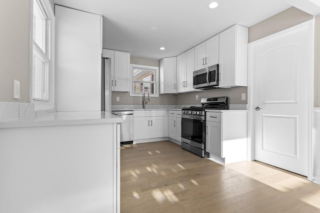 kitchen featuring stainless steel appliances, sink, white cabinets, and light hardwood / wood-style floors