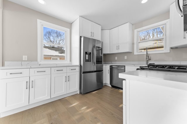 kitchen featuring appliances with stainless steel finishes, light wood-type flooring, and white cabinets