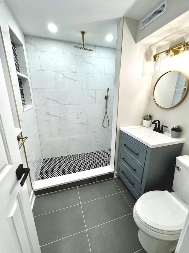 bathroom with tiled shower, toilet, tile patterned floors, and vanity