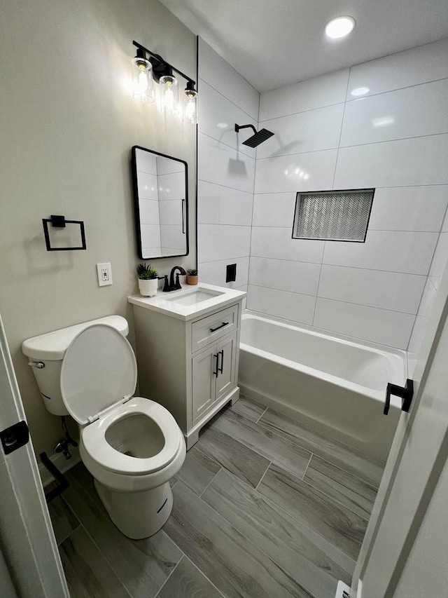 full bathroom featuring tiled shower / bath combo, toilet, and vanity