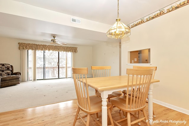 dining area featuring light wood-type flooring and ceiling fan with notable chandelier