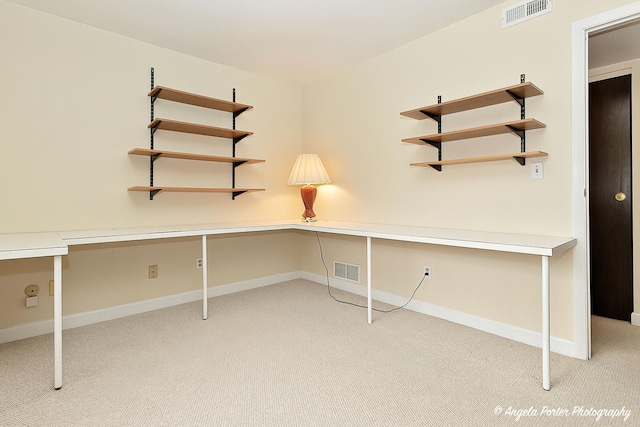 unfurnished office featuring built in desk and light colored carpet