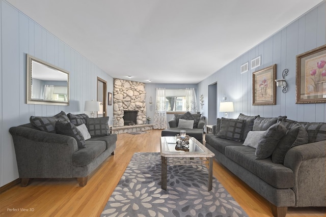 living room with a stone fireplace and light hardwood / wood-style floors