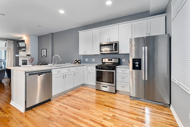 kitchen featuring sink, white cabinetry, light hardwood / wood-style flooring, appliances with stainless steel finishes, and kitchen peninsula