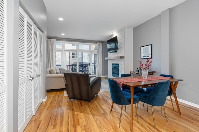 dining space featuring a stone fireplace and light hardwood / wood-style flooring