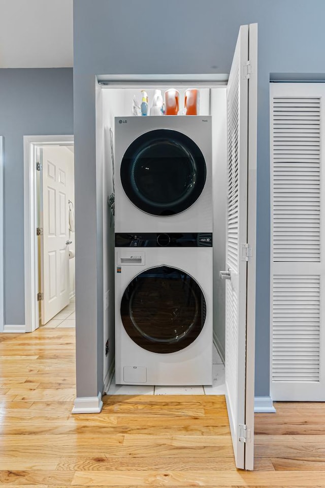 washroom with stacked washer and dryer and light wood-type flooring