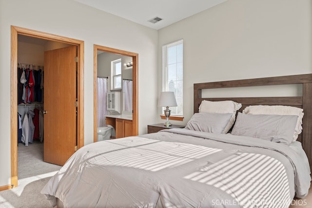 carpeted bedroom with ensuite bath, a spacious closet, and a closet