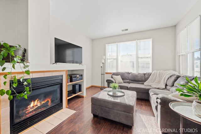 living room featuring a tile fireplace and dark wood-type flooring