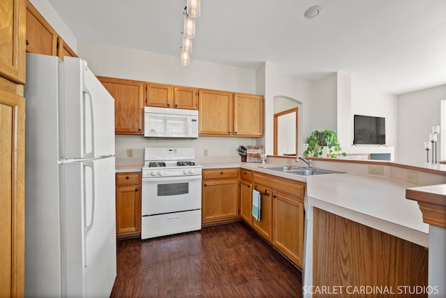 kitchen with white appliances, dark hardwood / wood-style floors, kitchen peninsula, and sink