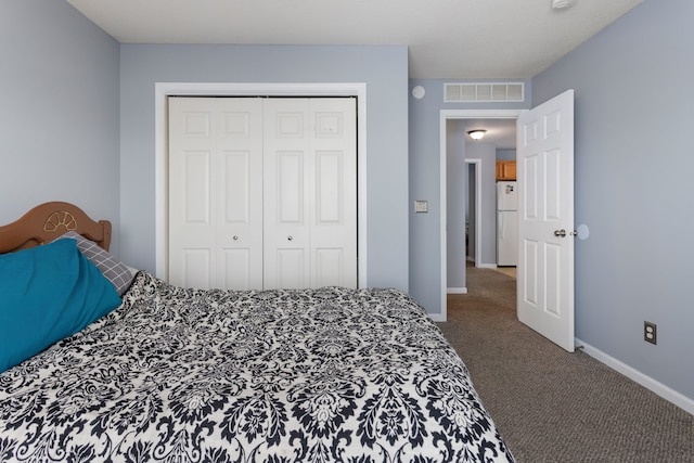 bedroom with white refrigerator, carpet, and a closet