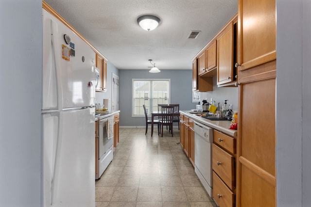 kitchen with white appliances, hanging light fixtures, and a textured ceiling