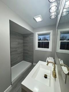 bathroom featuring vanity, wood-type flooring, and tiled shower