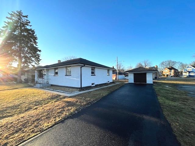 view of side of home with a garage, an outdoor structure, and a lawn