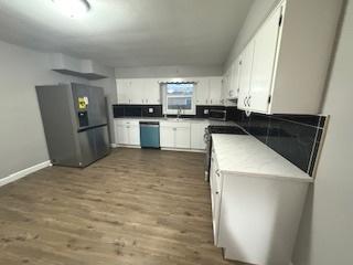 kitchen with stainless steel appliances, dark wood-type flooring, and white cabinets