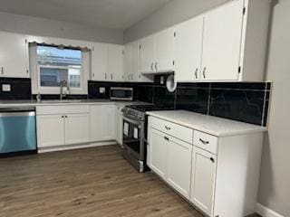 kitchen with stainless steel appliances, white cabinetry, sink, and dark hardwood / wood-style flooring