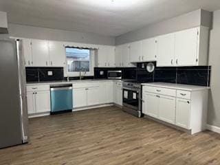 kitchen featuring stainless steel appliances, white cabinetry, and dark wood-type flooring