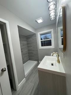 bathroom with tiled shower and vanity