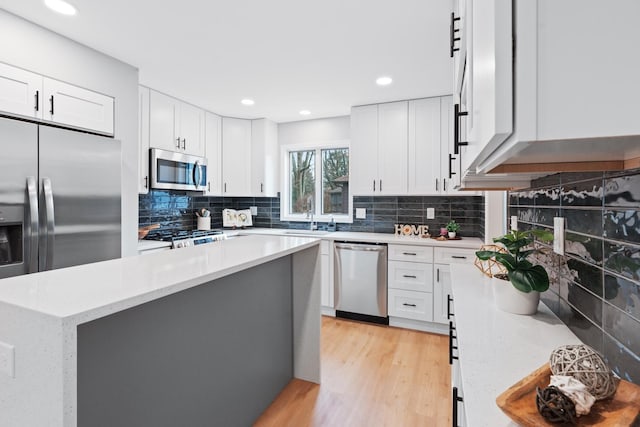 kitchen featuring sink, white cabinetry, light stone countertops, a center island, and stainless steel appliances