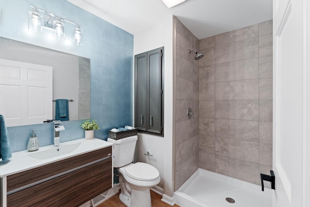 bathroom with vanity, toilet, and a tile shower