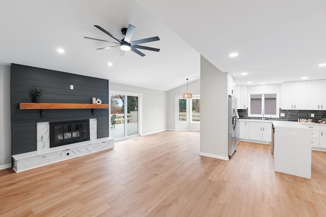 kitchen with a fireplace, decorative backsplash, white cabinets, decorative light fixtures, and lofted ceiling