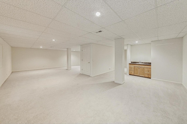 basement with sink, light carpet, and a drop ceiling